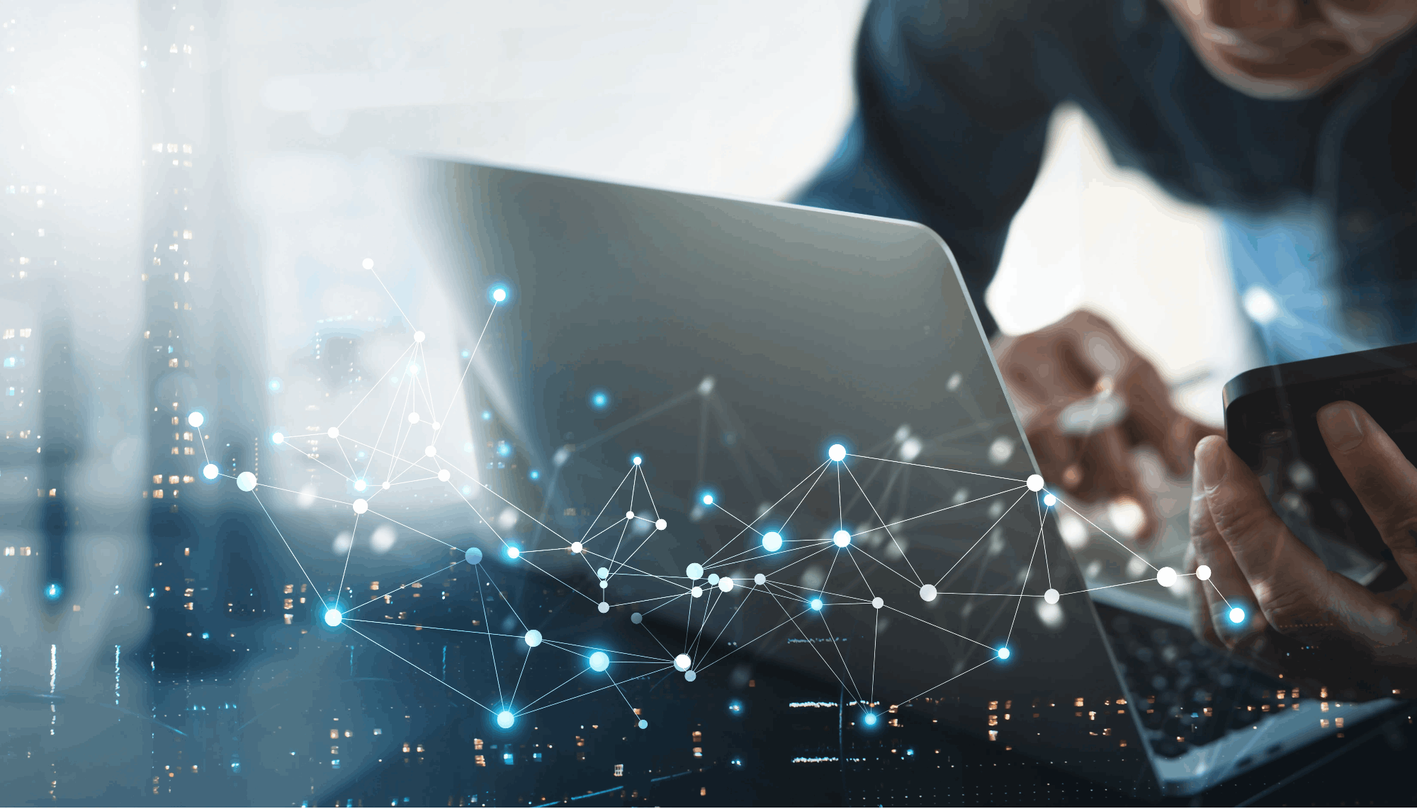 Profesional usando portátil y móvil con red digital simbolizando la conectividad y la transformación digital en la empresa.